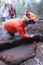 Archaeologists mapping a feature which is outlined by the orange flags. Photograph by Lance Cpl. Nikki S. Phongsisattanak